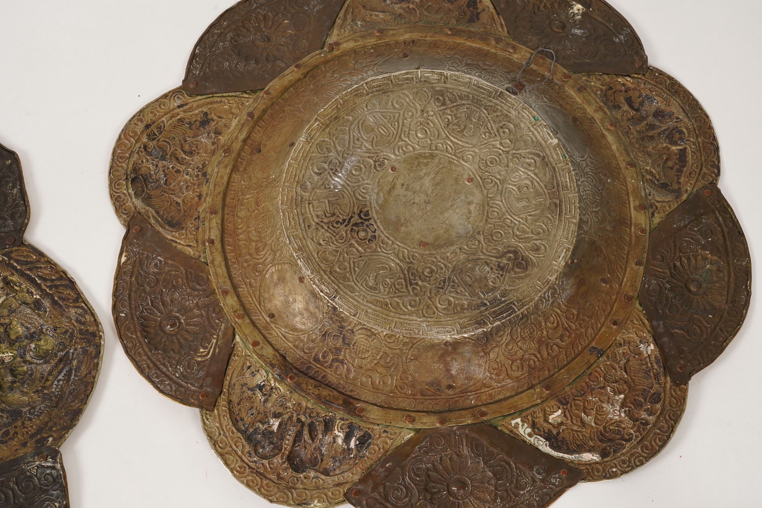 A graduated set of three Nepalese repoussé white metal and brass chargers, first half 20th century